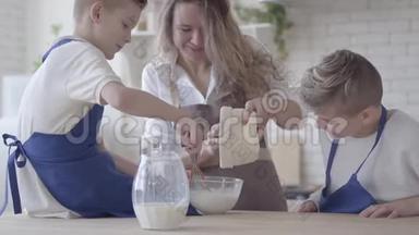 肖像漂亮的女人和她的两个儿子在厨房里<strong>做</strong>饭<strong>做</strong>面团，男孩们帮助母亲<strong>做</strong>食物。 妈妈